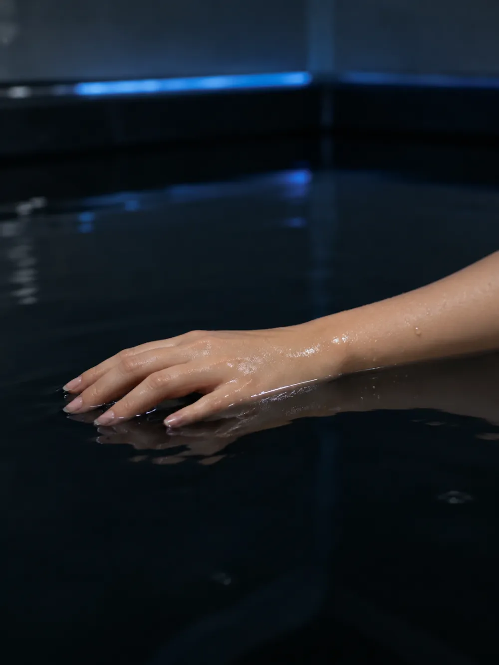 A relaxed hand resting on the dark float water