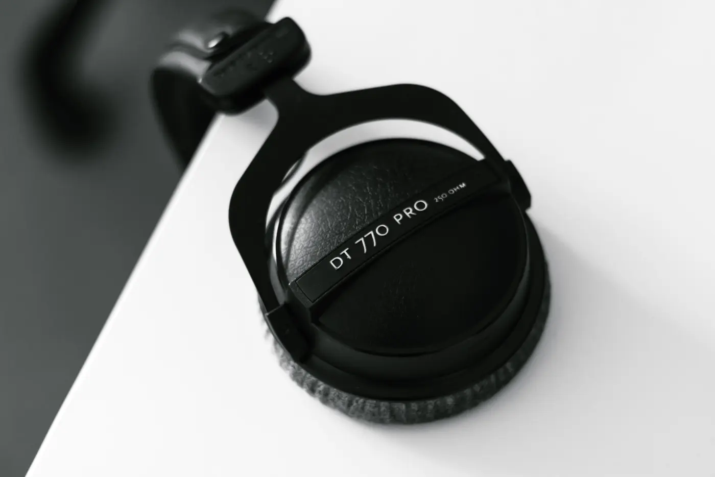 Top view of a pair of over-ear headphones hanging from the edge of a wooden desk