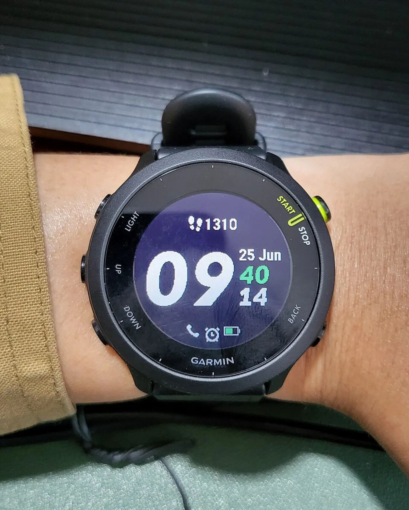A black running smartwatch on a wrist showing the time and a step count