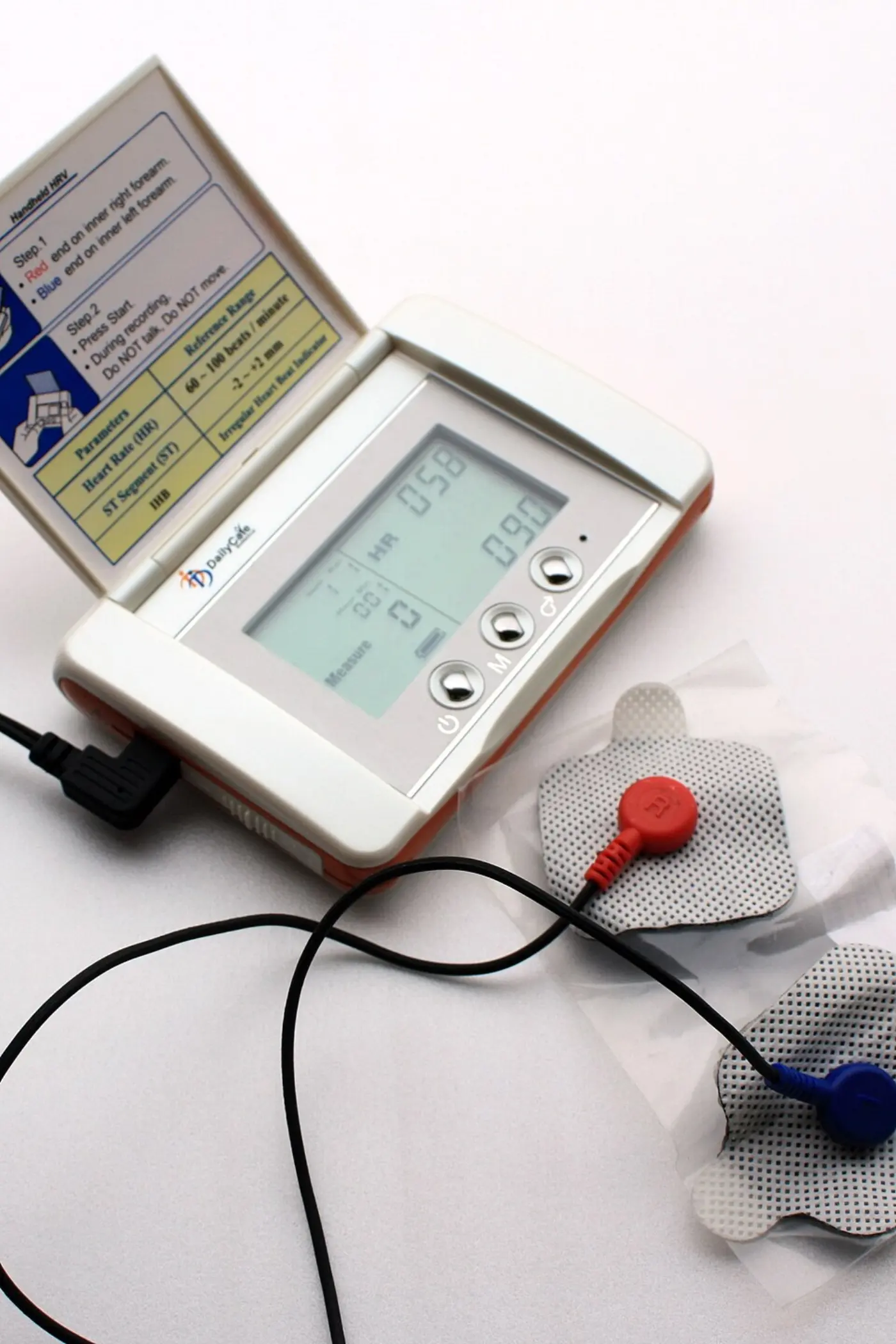 A small portable heart rate variability monitor with a flip-up instruction card, connected by wires to two foam electrodes