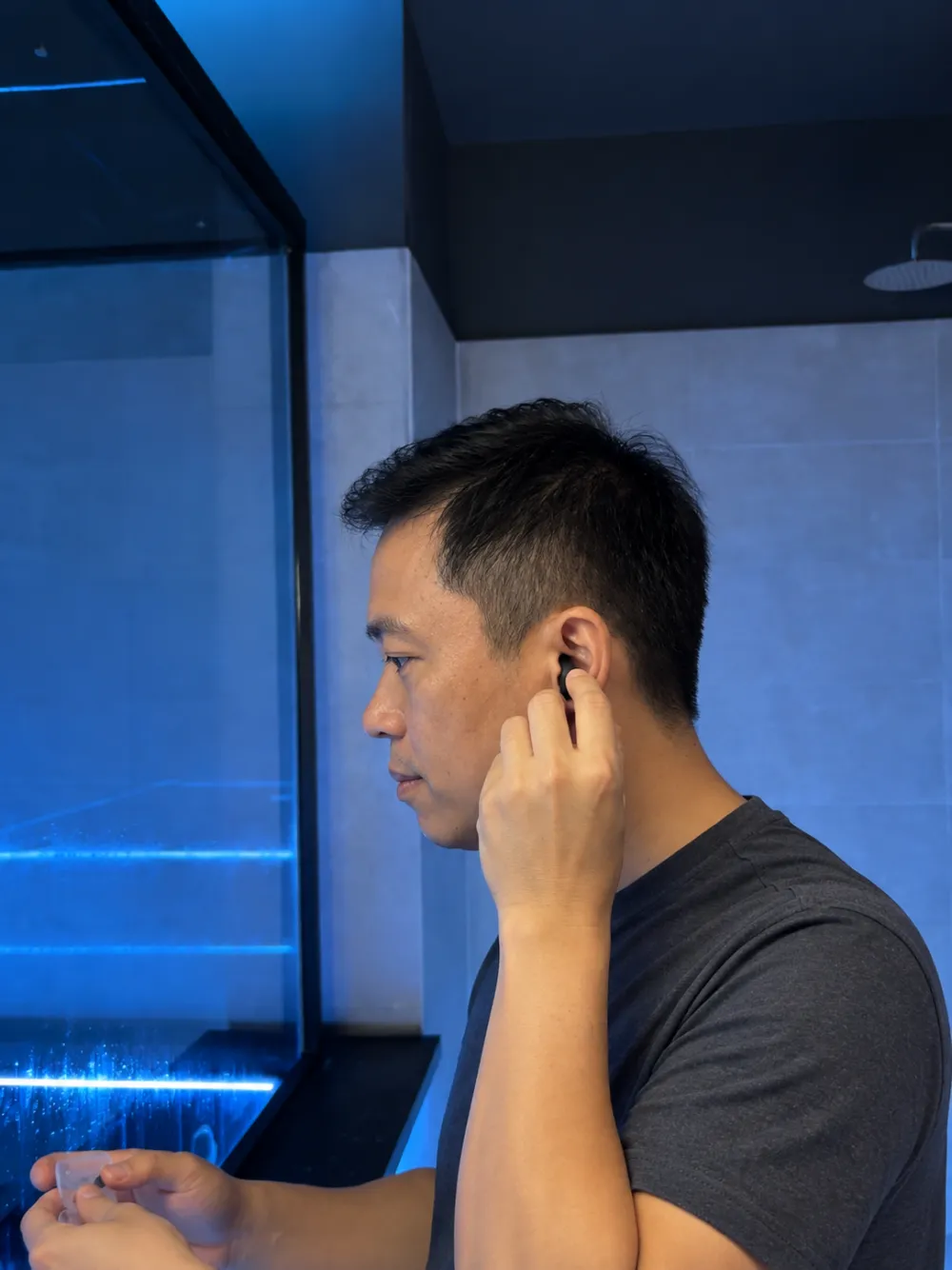 Hombre poniéndose tapones para los oídos antes de flotar, con luz azul detrás