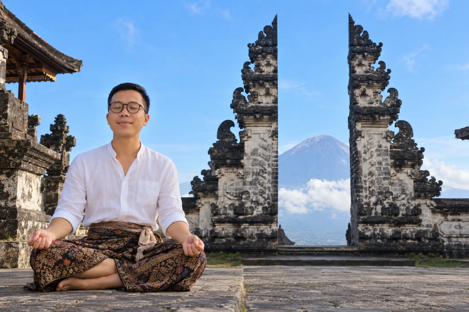Đức meditating cross-legged at the Gates of Heaven, Pura Lempuyang, with Mount Agung behind