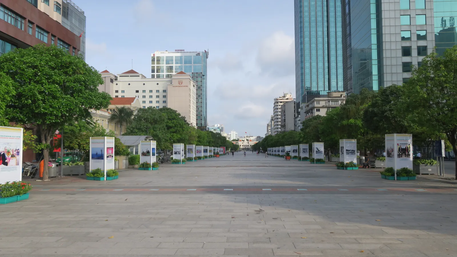 An almost empty Nguyen Hue pedestrian boulevard in central Ho Chi Minh City in soft early morning light, lined with trees and tall buildings