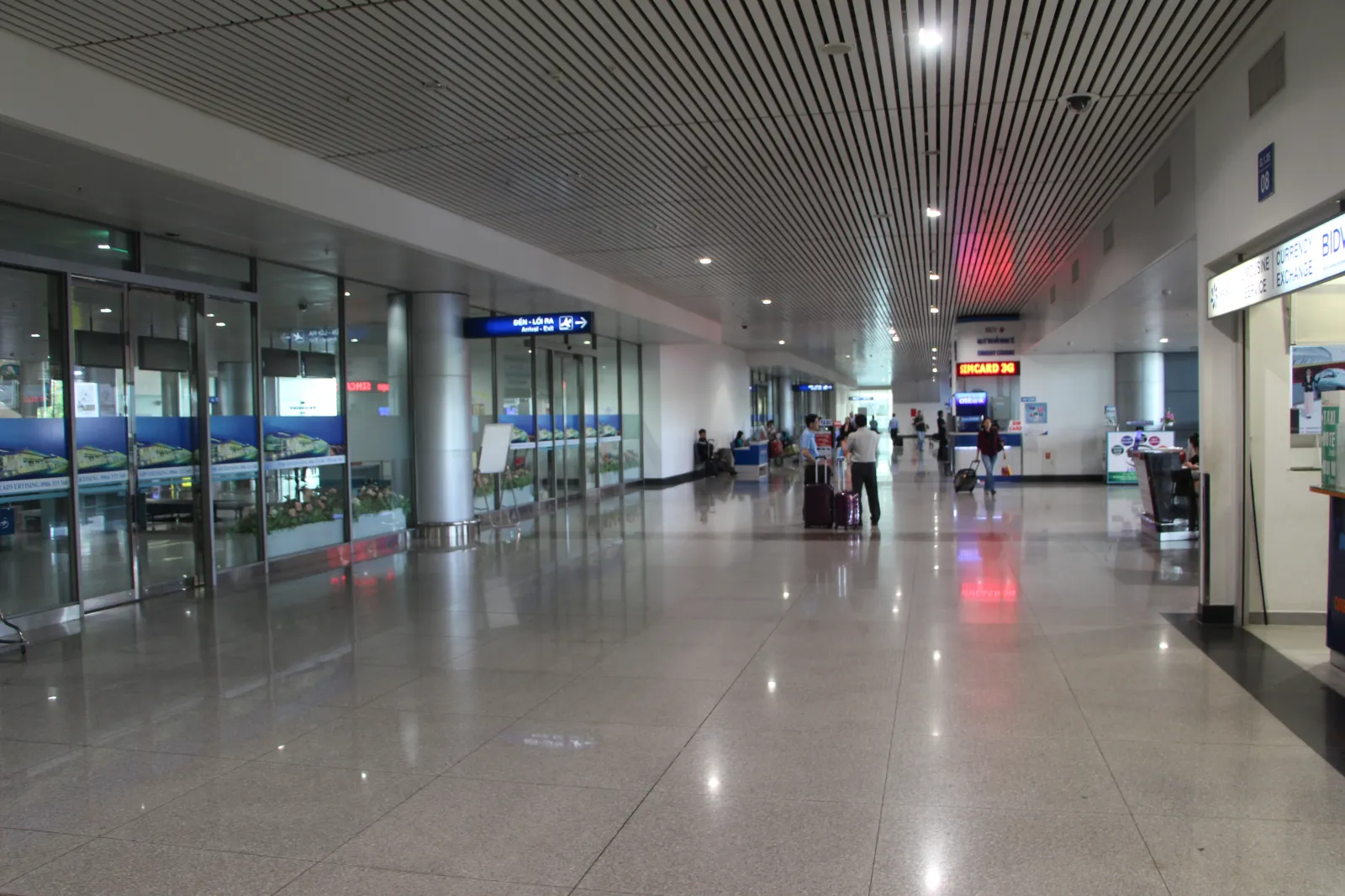 The quiet international arrivals hall at Tan Son Nhat Airport with a SIM card counter and a currency exchange desk