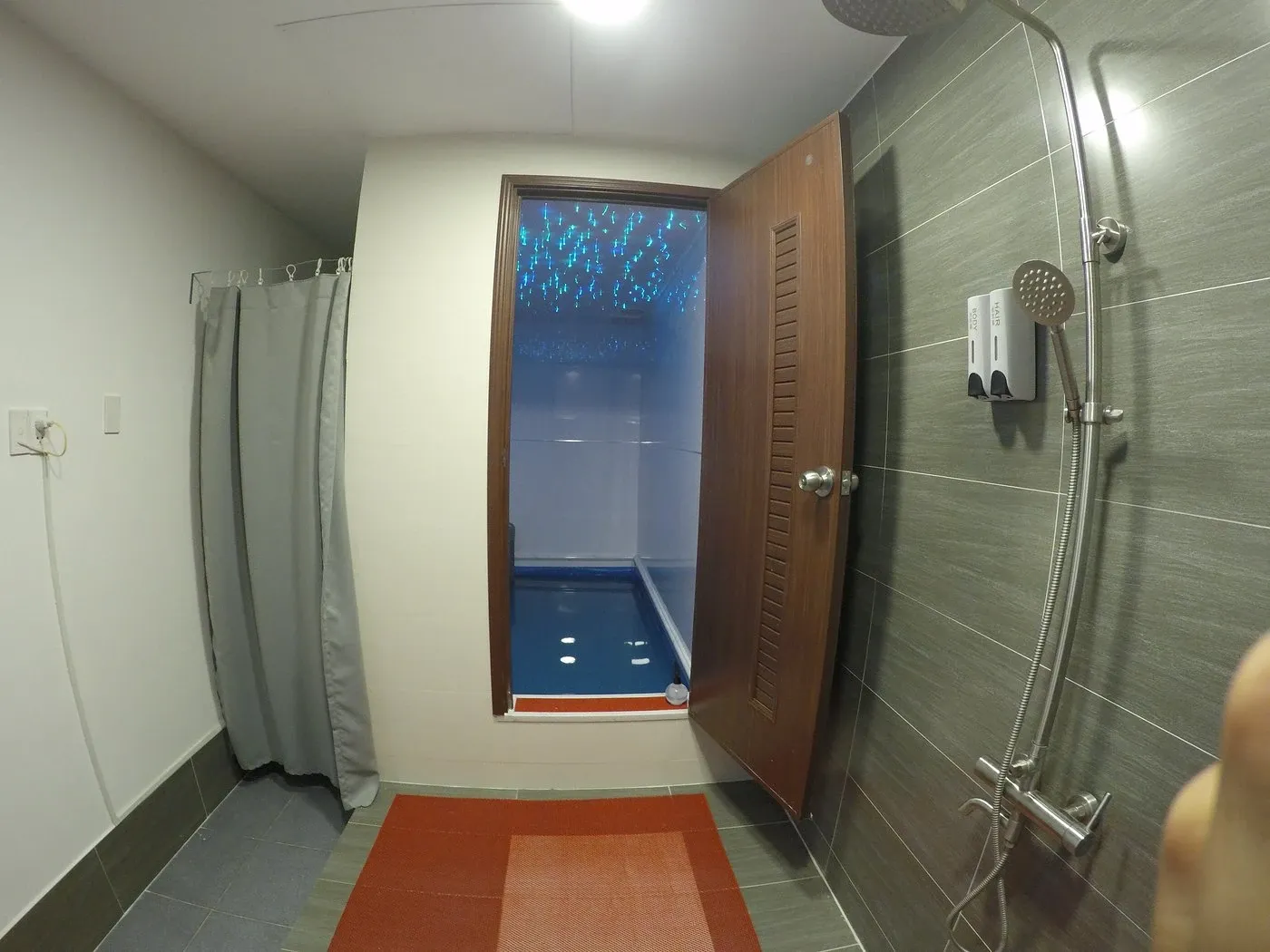 An enclosed float cabin with its door open, blue starry ceiling and a shower in front