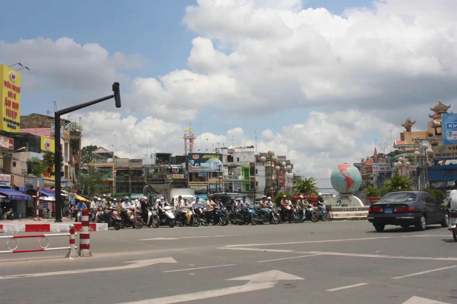 Ngã tư rộng ở TP.HCM, rất đông người đi xe máy dừng chờ ánh sáng đỏ dưới bầu trời nhiều mây