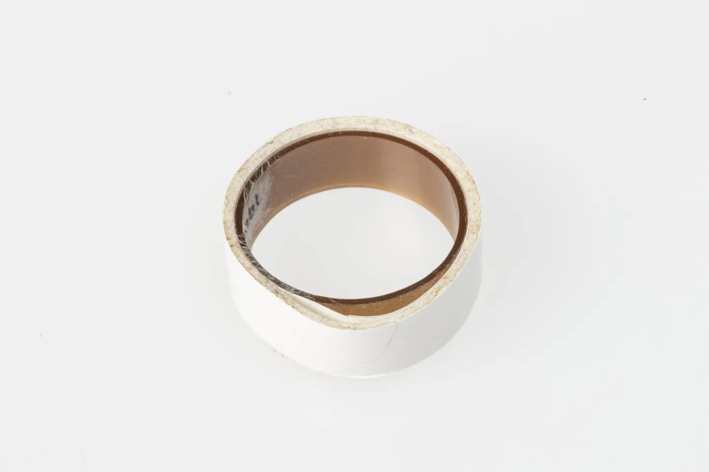 A small roll of white adhesive tape on a plain white background