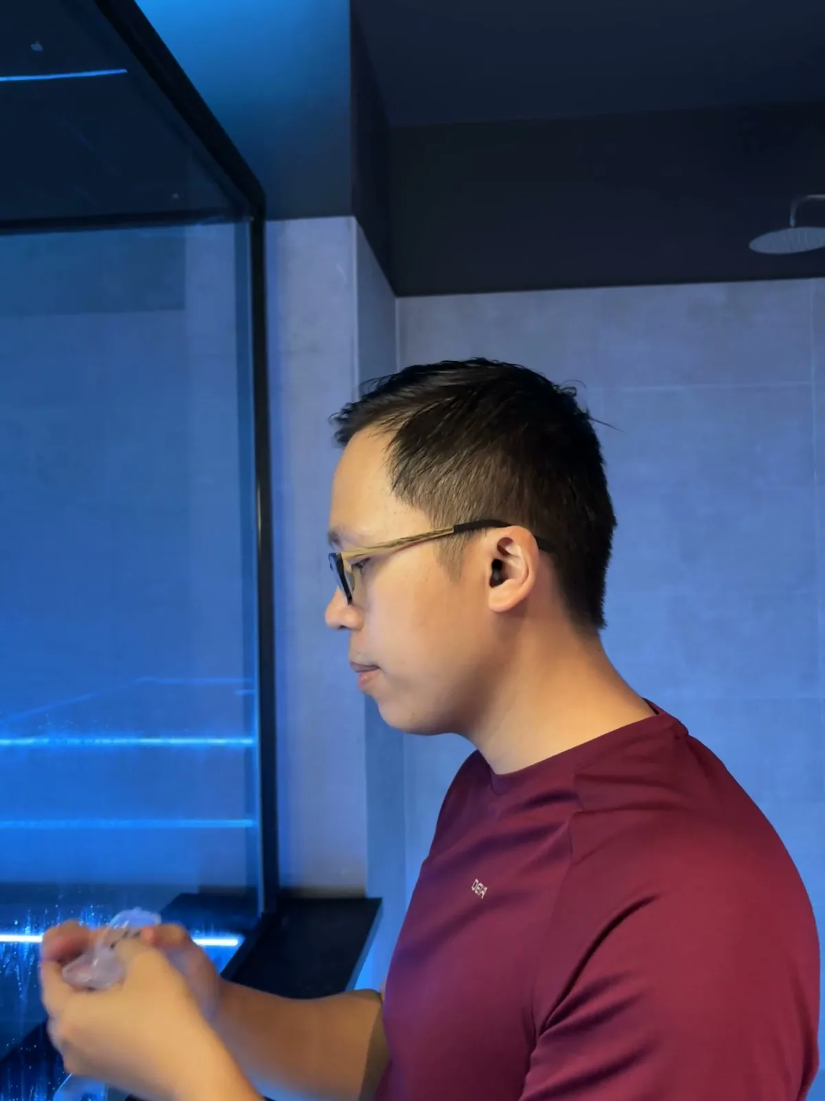 Hombre poniéndose tapones para los oídos antes de una flotación bajo una suave luz azul