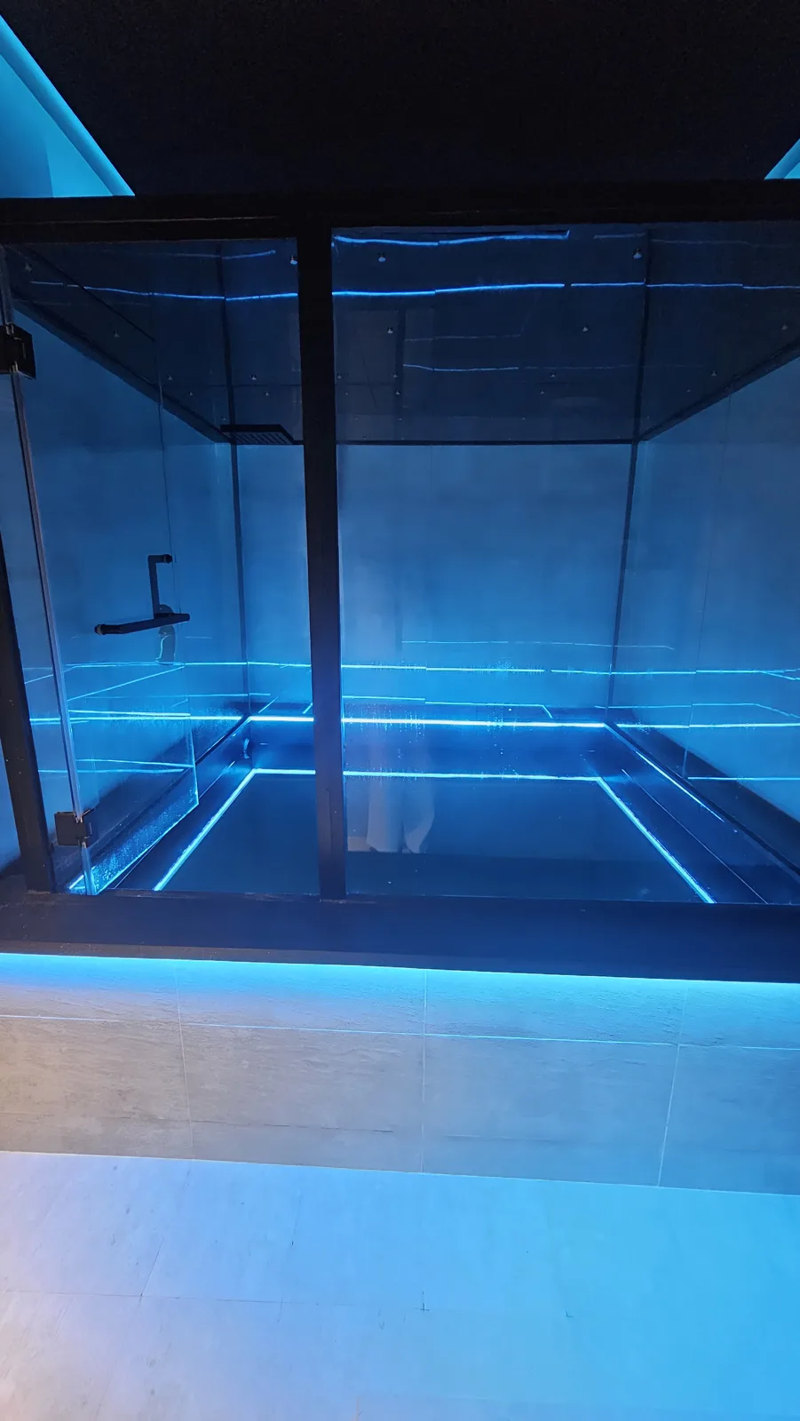 A float pool behind glass doors under soft blue light at Ōmni Space