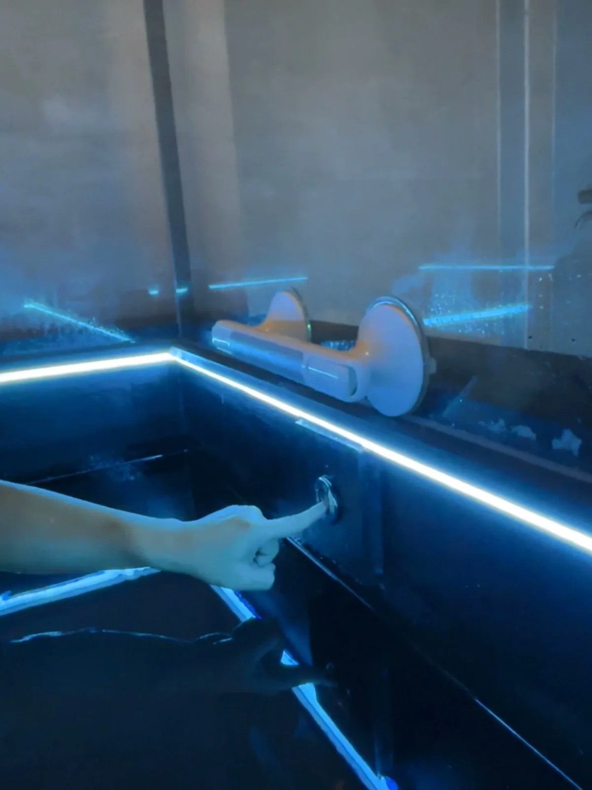 A hand resting on the dark, still water of a float pool