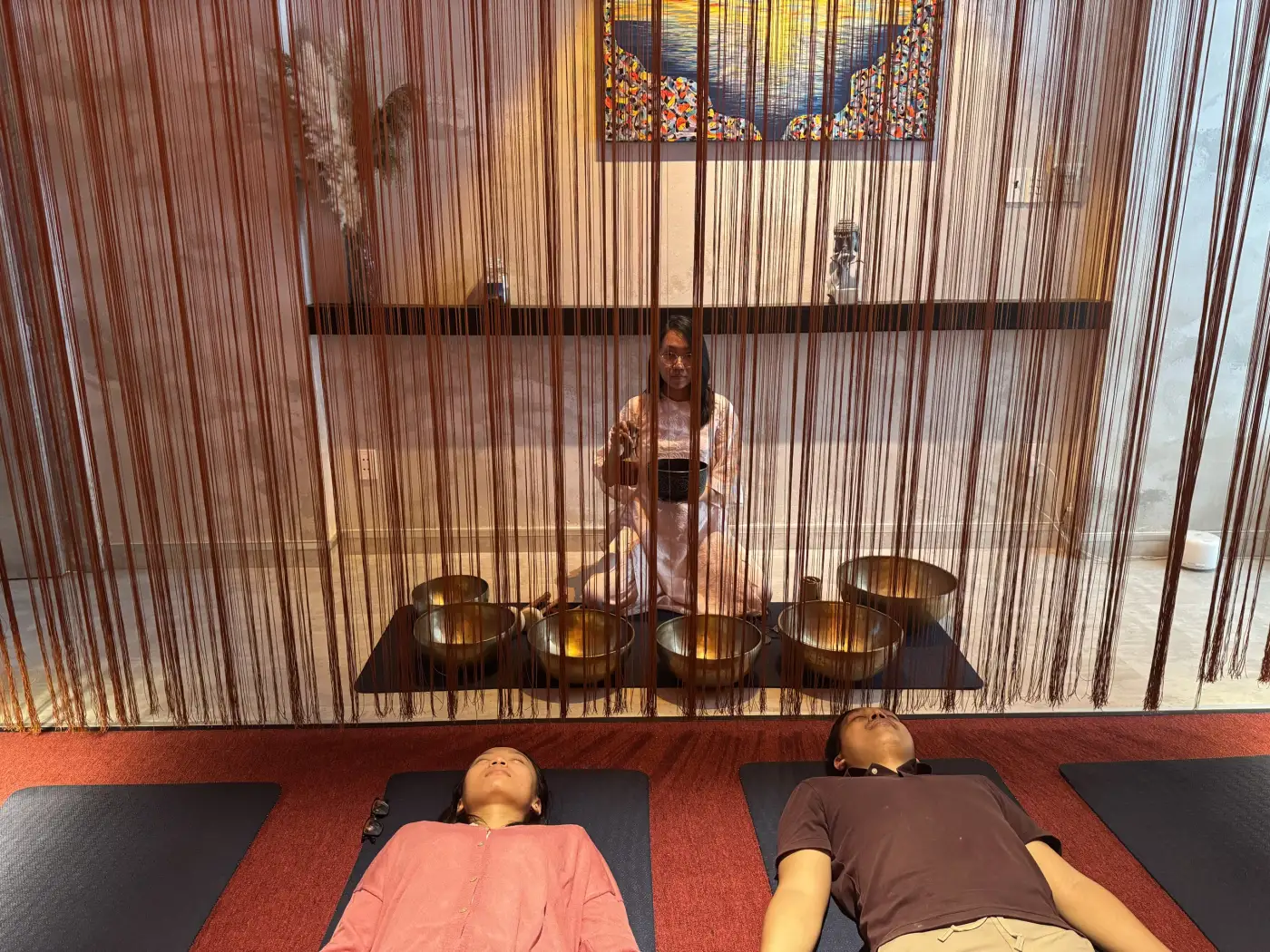 Guests lying on mats during a singing-bowl sound bath at Ōmni Space