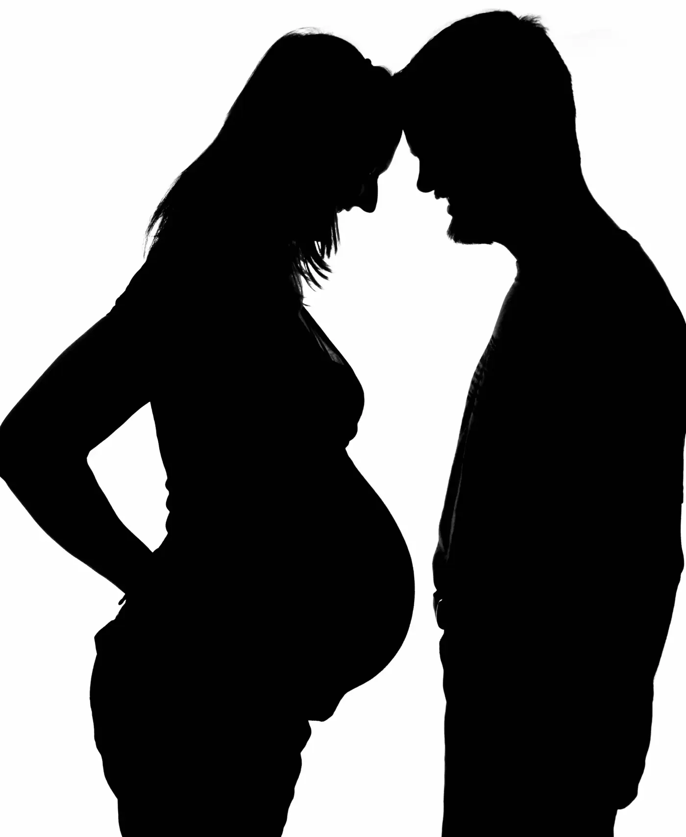 Black silhouette of a heavily pregnant woman and her partner standing forehead to forehead on a white background