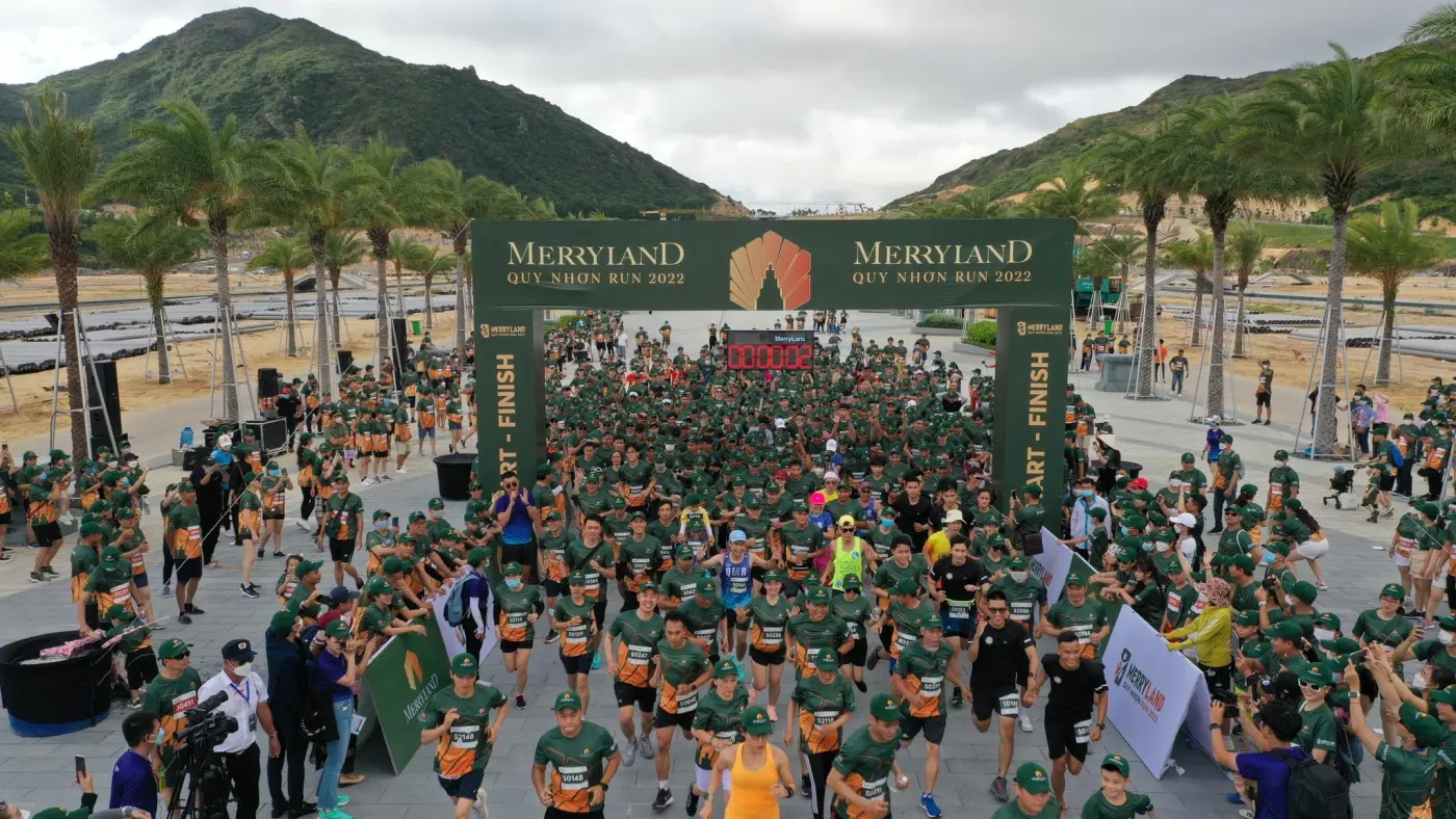 Hundreds of runners in matching shirts setting off under a start arch at a road race in Quy Nhơn, Vietnam