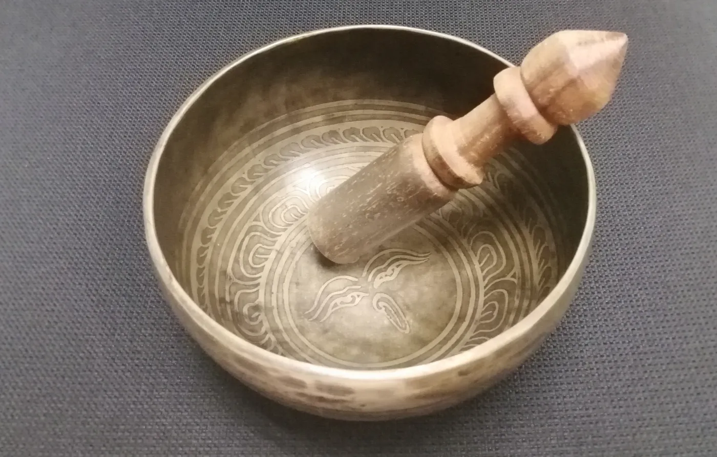 Brass singing bowl with an engraved pattern and a wooden striker resting inside