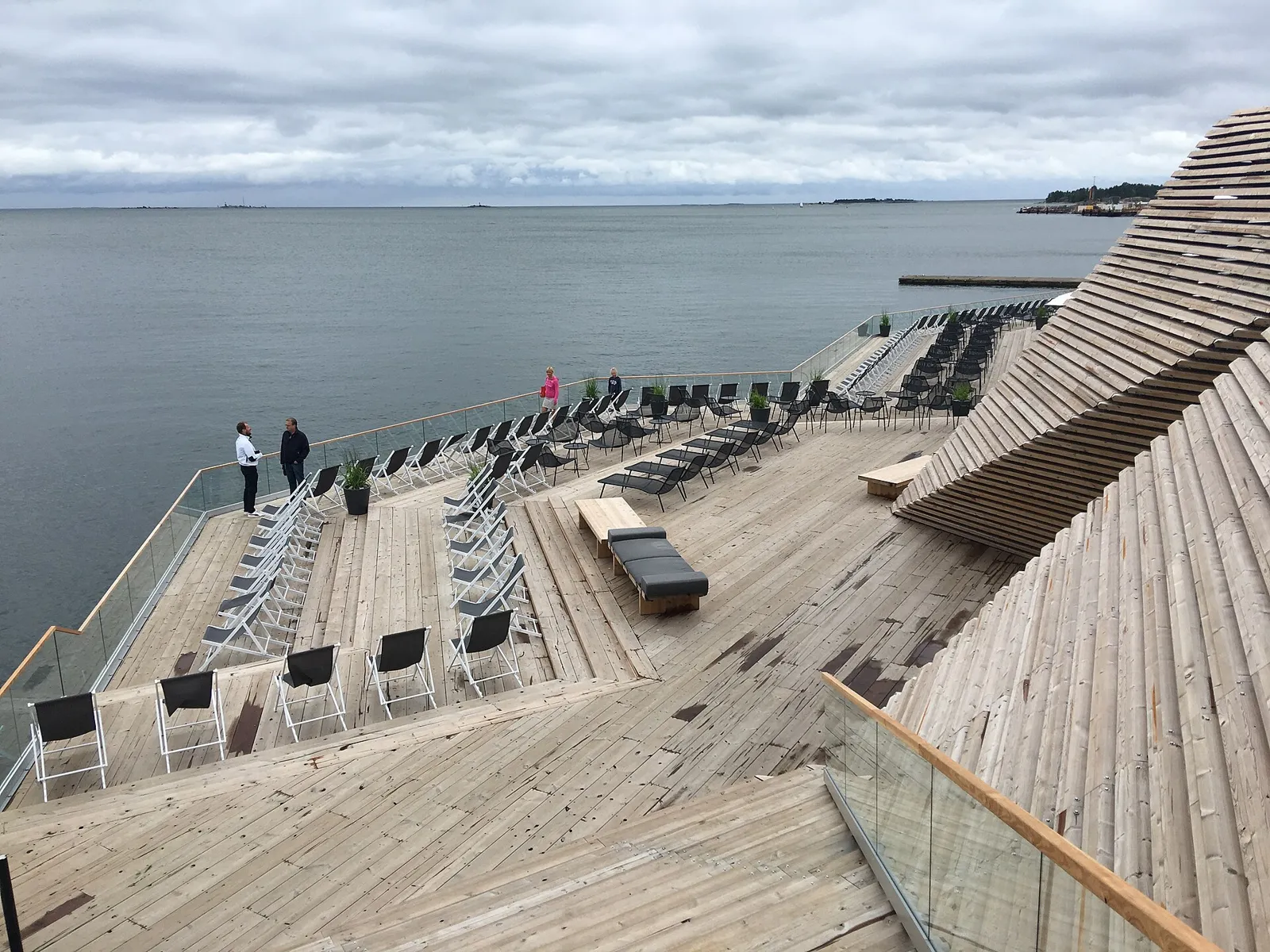 Wooden sauna terrace with lounge chairs facing the sea