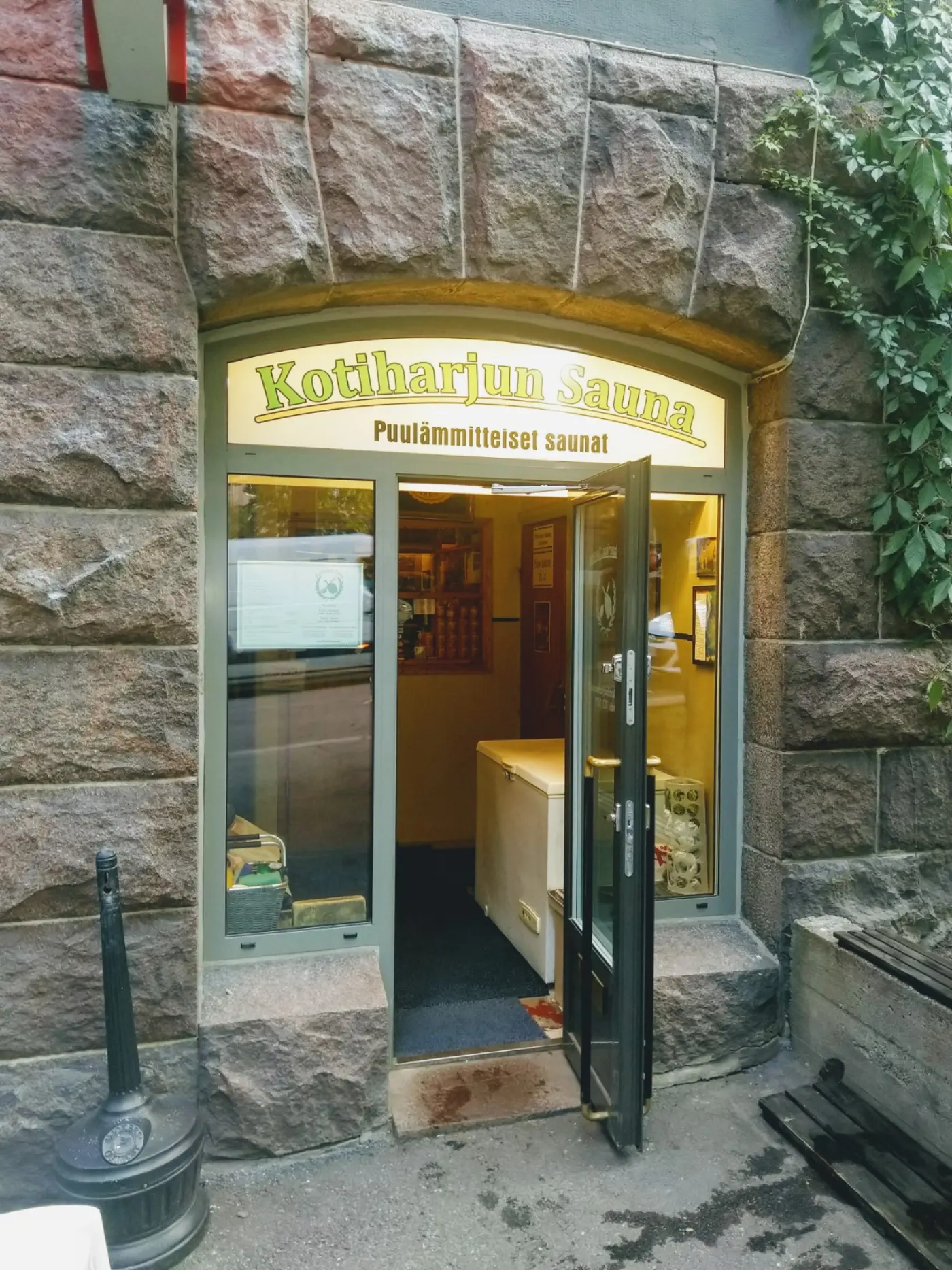 Entrance of Kotiharju public sauna in Helsinki with its name sign above a glass door