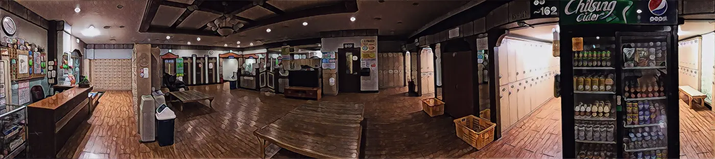 Wide view of a jjimjilbang common lounge with lockers, wooden floor and a drinks fridge