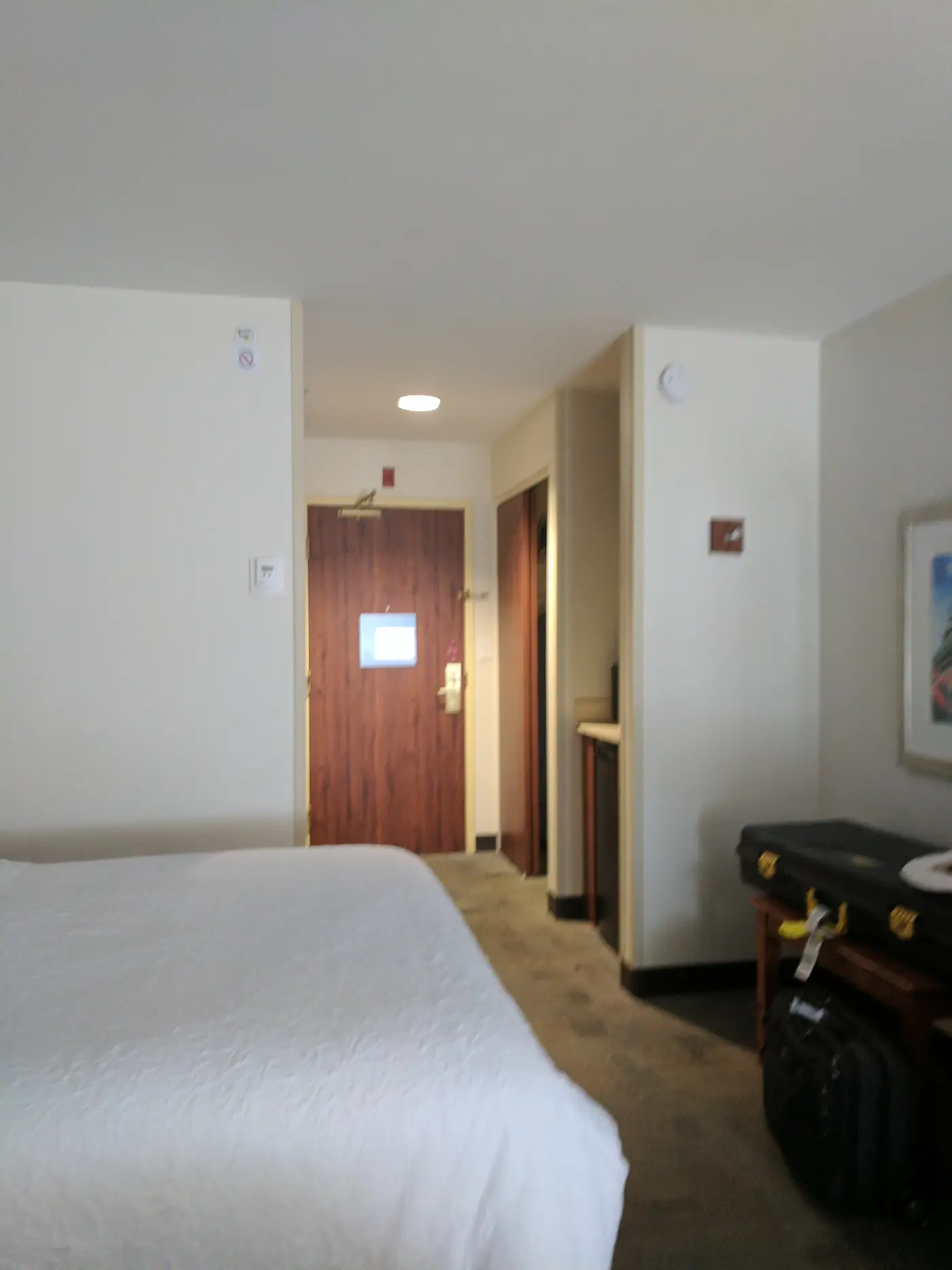 A made-up queen bed in a quiet hotel room