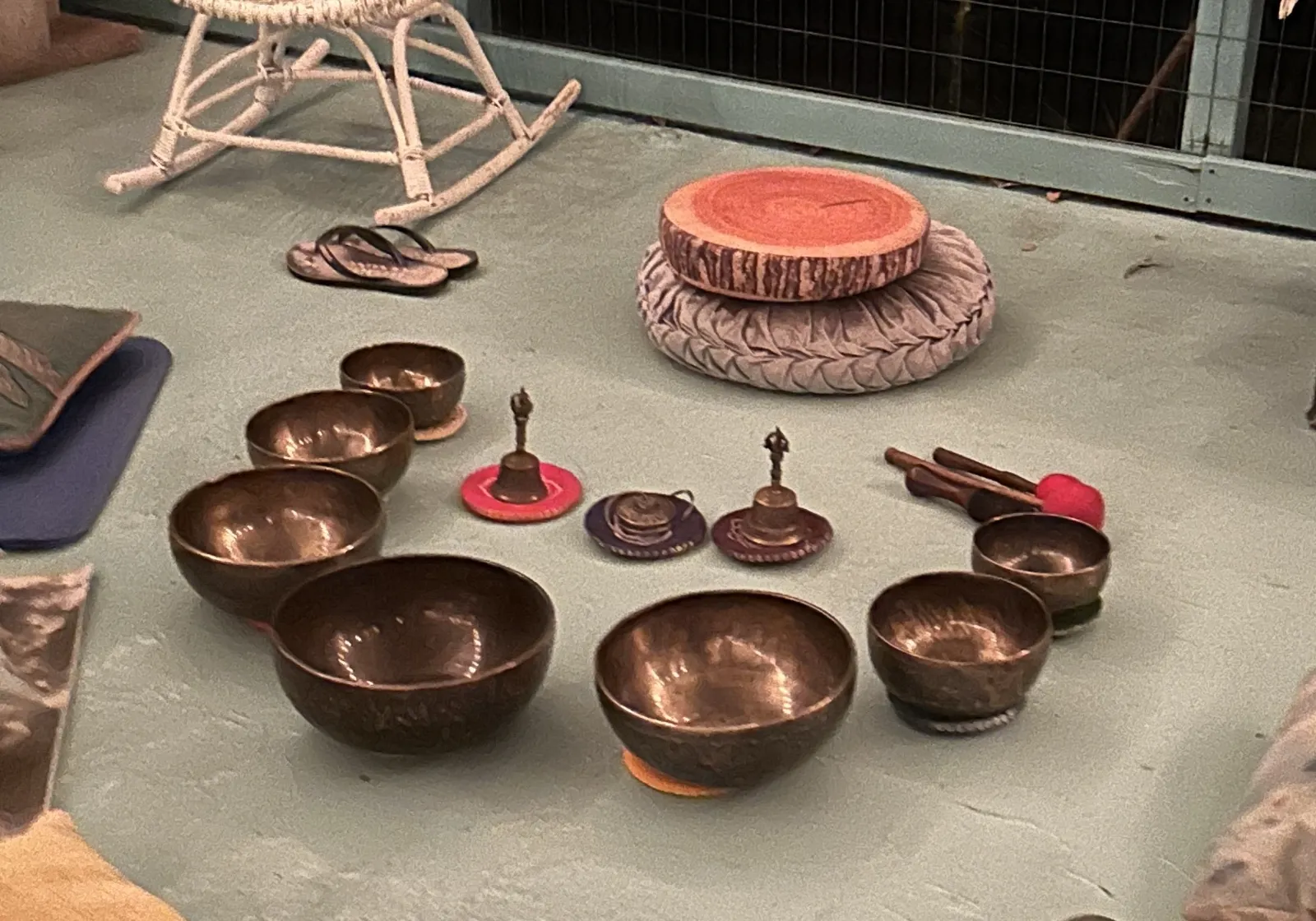 Copper singing bowls and small bells arranged in a circle on the floor