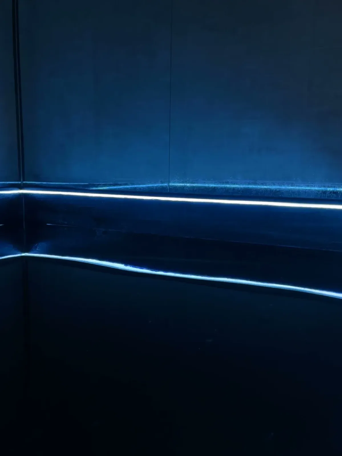 Still, dark water in a float pool, with a thin line of soft blue light running along the wall just above the surface