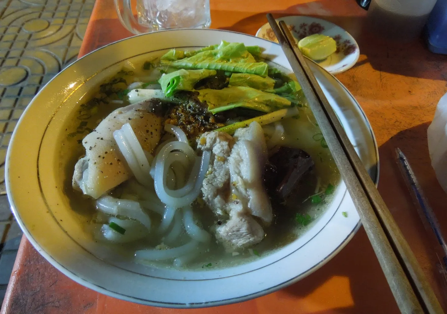 Cuenco de fideos gruesos bánh canh con cerdo, verduras y palillos