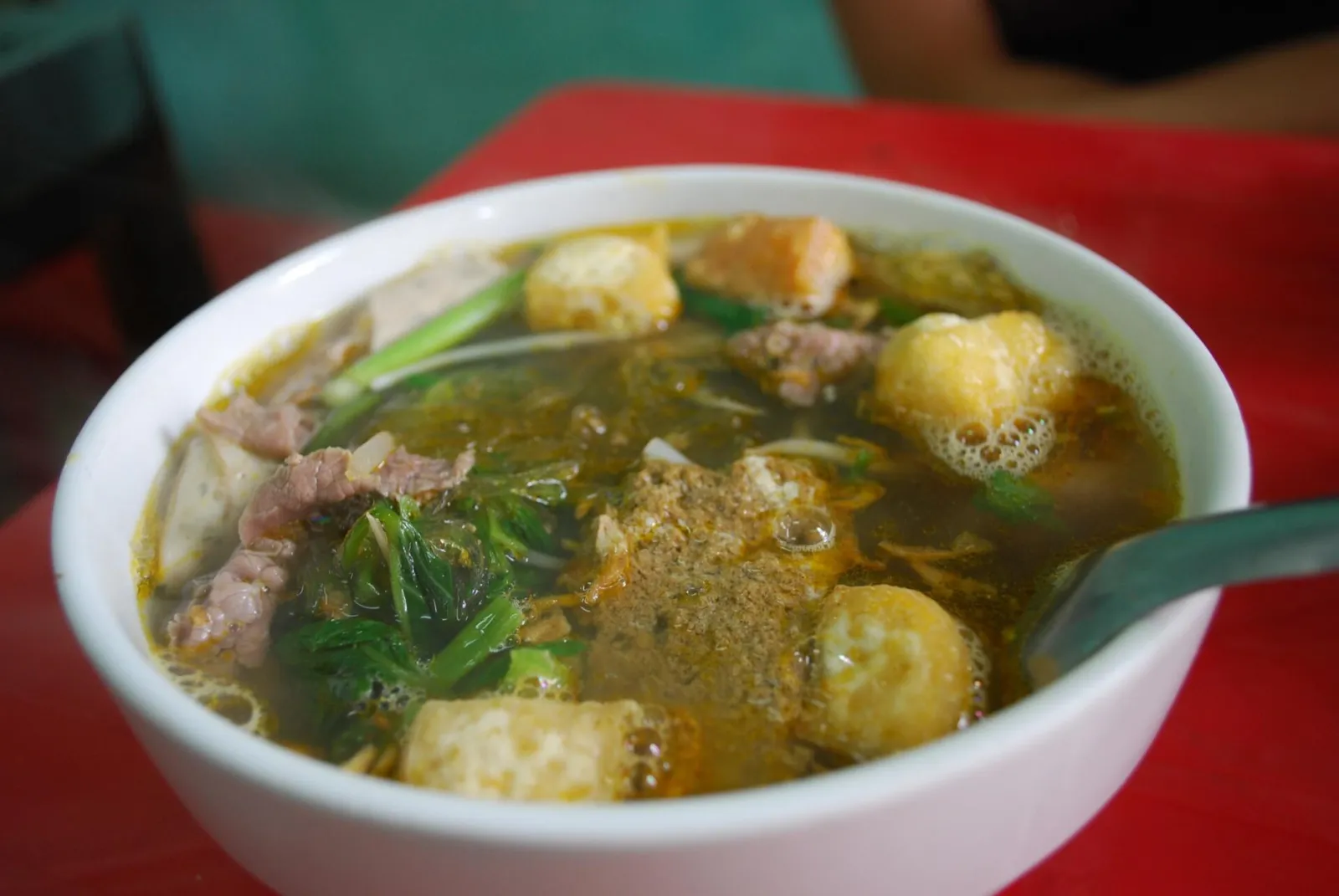 Cuenco de bún riêu con pasta de cangrejo, tofu frito, cerdo y verduras