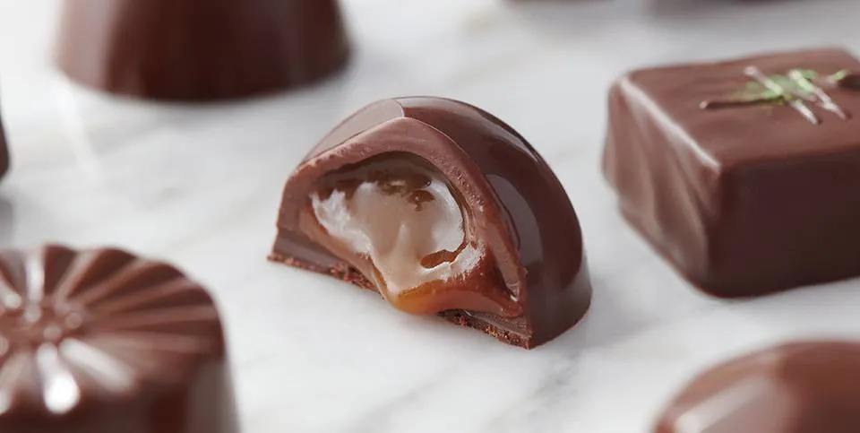 Bombones de chocolate, uno cortado por la mitad mostrando un centro de caramelo