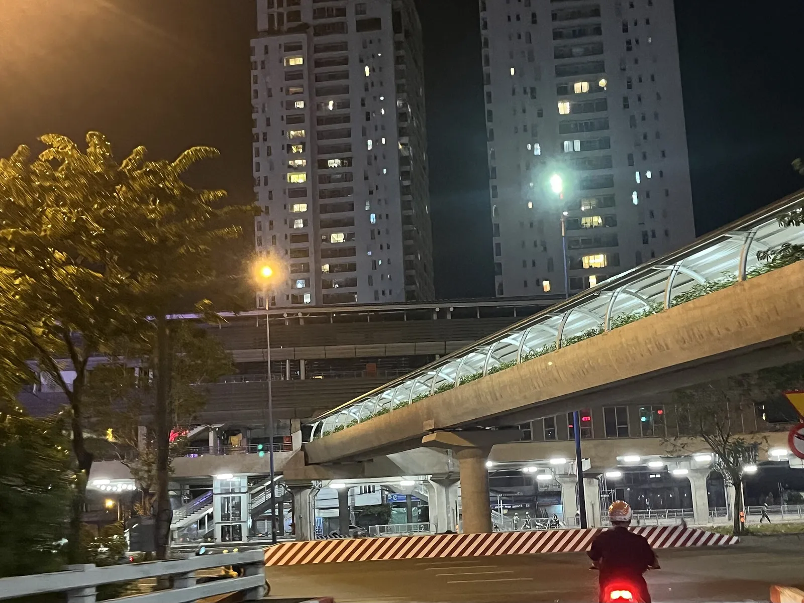 Pasarela peatonal cubierta sobre el bulevar que lleva a la estación de Thảo Điền, de noche